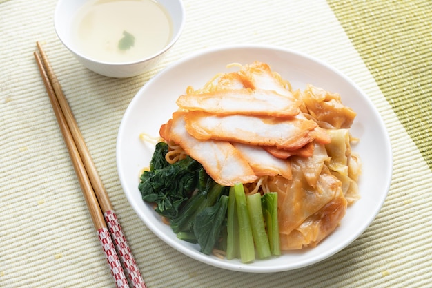 Foto fideos wonton de cerdo rojo en un plato blanco listo para comer, comida callejera tailandesa.
