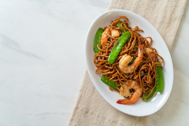 fideos yakisoba salteados con guisantes y camarones - estilo de comida asiática