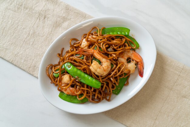 fideos yakisoba salteados con guisantes y camarones - estilo de comida asiática