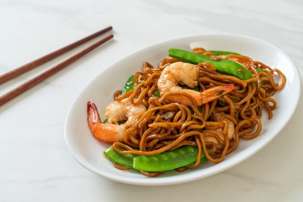 fideos yakisoba salteados con guisantes y camarones - estilo de comida asiática