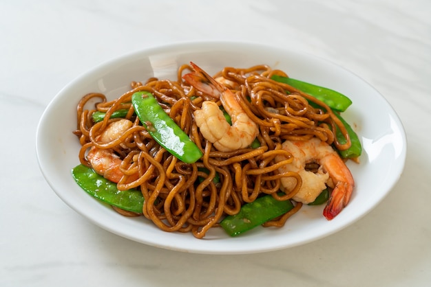 fideos yakisoba salteados con guisantes y camarones - estilo de comida asiática