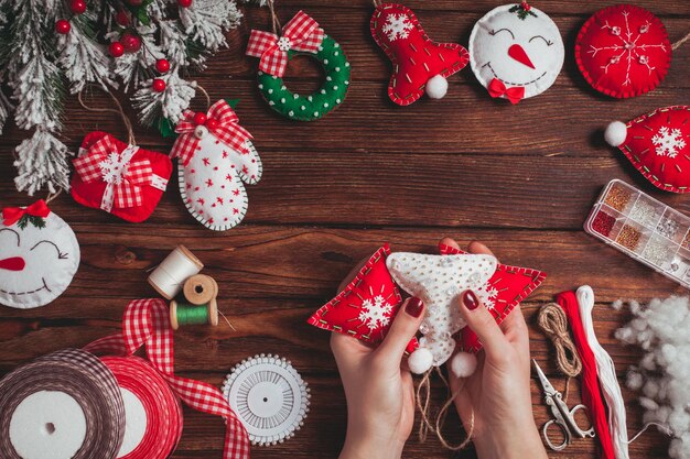 Fieltro adornos navideños en la mesa de madera - mujer se prepara para artesanías