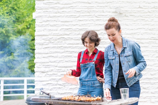 Fiesta de barbacoa en el jardín con mamá y su hija a la parrilla en un país