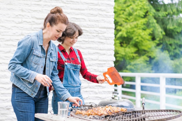 Fiesta de barbacoa en el jardín con mamá y su hija a la parrilla en un país