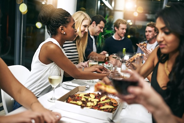 Fiesta de comida y pizza con amigos en el restaurante para celebrar el vino y el evento social Feliz diversidad y noche con un grupo de personas comiendo juntas por el lujo hambriento y el tiempo libre