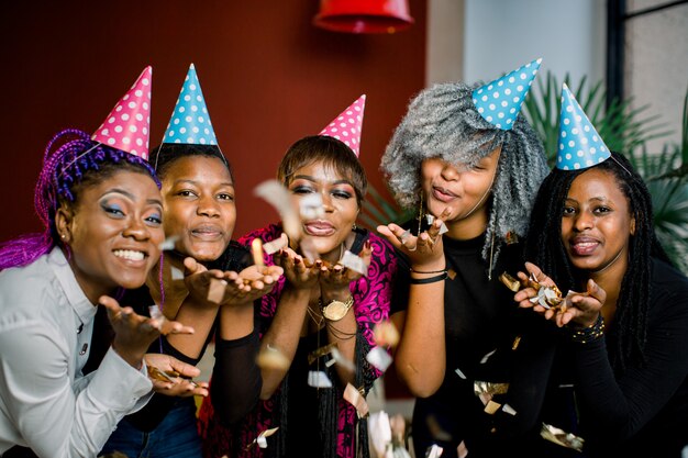 Fiesta de confeti Feliz joven grupo africano de personas celebrando la víspera de año nuevo y soplando confeti