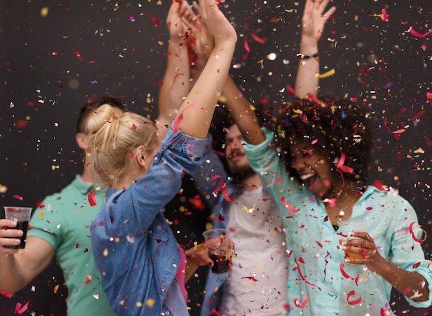 fiesta de confeti Grupo multiétnico de jóvenes felices celebrando la víspera de año nuevo mientras bailan y se divierten en casa