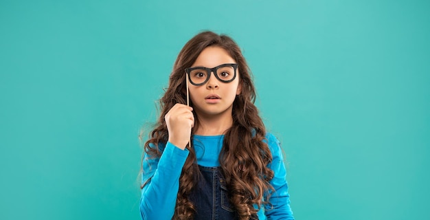 Fiesta de cumpleaños celebración navideña divirtiéndose vamos a celebrar niño con pelo largo y rizado sobre fondo azul asustado niño divertido con gafas adolescente fiestero