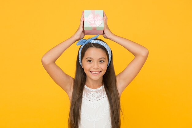 Foto fiesta de cumpleaños. compre regalo. las compras en línea. servicio de entrega. concepto de regalo perfecto. celebre las vacaciones de primavera. lindo vestido adorable de niño pequeño. caja de regalo de asimiento de pelo largo de niña. regalo para niña adolescente.