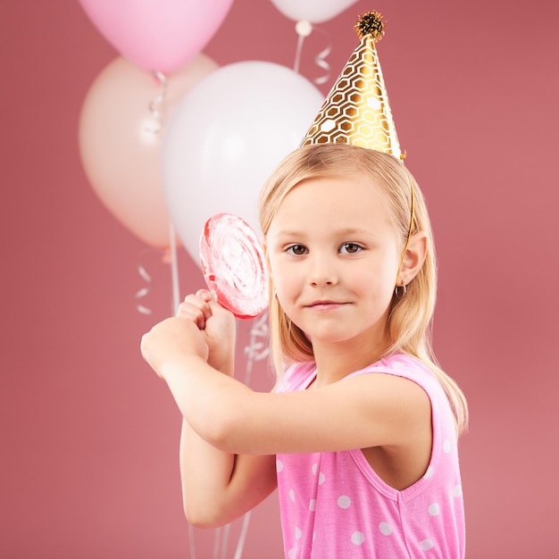 Fiesta de cumpleaños de niña y niño y globos en el retrato de estudio piruleta y sombrero para el evento de celebración y fondo rojo Cara y caramelo de niña con regalo y decoración para celebrar