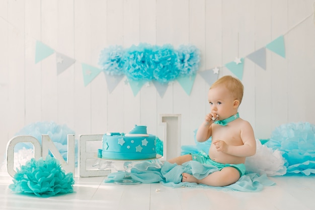 Fiesta de cumpleaños para un niño de un año en guirnaldas azules y turquesas y un concepto de vacaciones de pastel