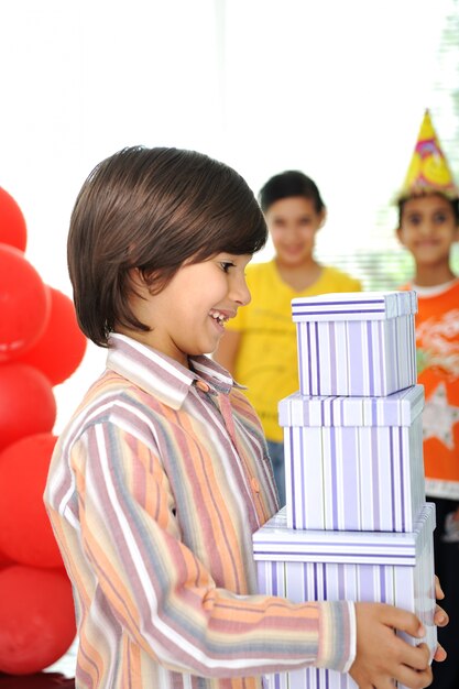 Foto fiesta de cumpleaños, niños felices celebrando, globos y regalos alrededor