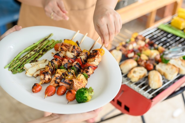 Fiesta Grill y Barbacoa en casa. Cocinar cerdo, ternera, pollo, mariscos y verduras a la barbacoa. Estilo de vida familiar y actividad al aire libre de amigos.