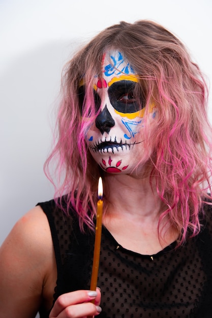 Foto fiesta de halloween, retrato de una niña con maquillaje sosteniendo una vela en la mano.