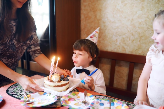 Fiesta infantil en gorras celebrando cumpleaños con pastel y globos en casa.