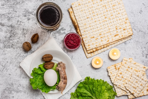 Fiesta judía Pascua con vino, matza y plato de seder en gris.