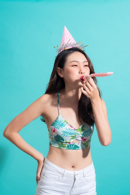 Fiesta mujer posando contra la pared azul en elegante traje de verano, sombrero de papel