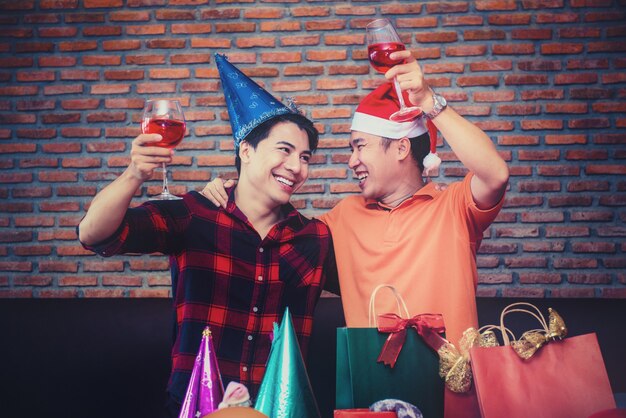 Fiesta de navidad y año nuevo con amigos. pareja gay bebiendo vino tinto en la noche de vacaciones.