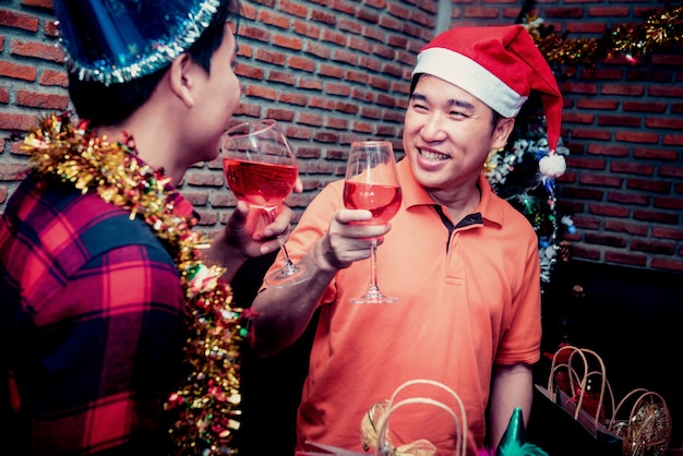 Fiesta de navidad y año nuevo con amigos. Pareja gay bebiendo vino tinto en la noche de vacaciones.