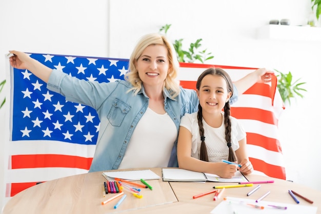 Foto fiesta patriótica. familia feliz, madre y su hija niña con bandera estadounidense en casa. estados unidos celebra el 4 de julio.