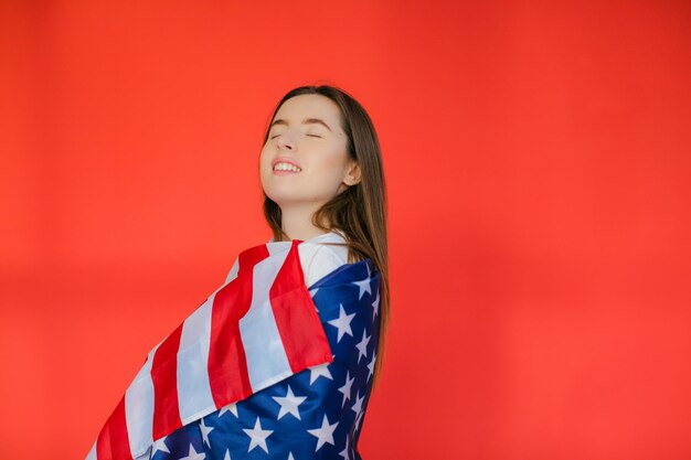 Fiesta patriótica Mujer joven feliz con bandera estadounidense sobre fondo rojo EE.UU. celebra el 4 de julio