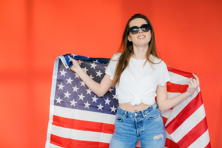 Fiesta patriótica Mujer joven feliz con bandera estadounidense sobre fondo rojo EE.UU. celebra el 4 de julio