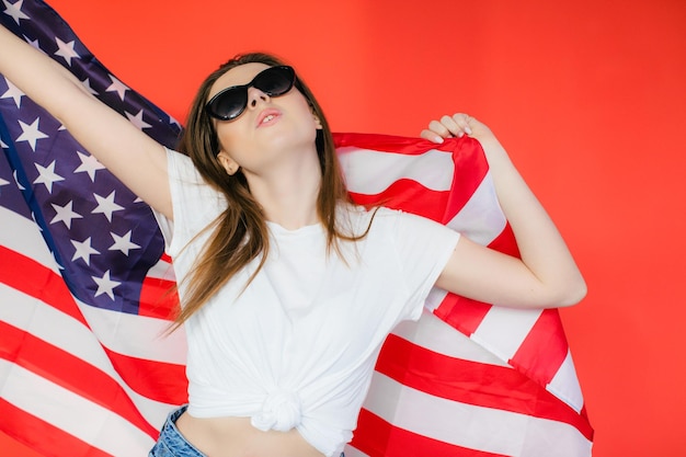 Fiesta patriótica Mujer joven feliz con bandera estadounidense sobre fondo rojo EE.UU. celebra el 4 de julio