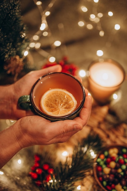 Fiesta del té por la noche con luces de Navidad, té caliente y dulces.