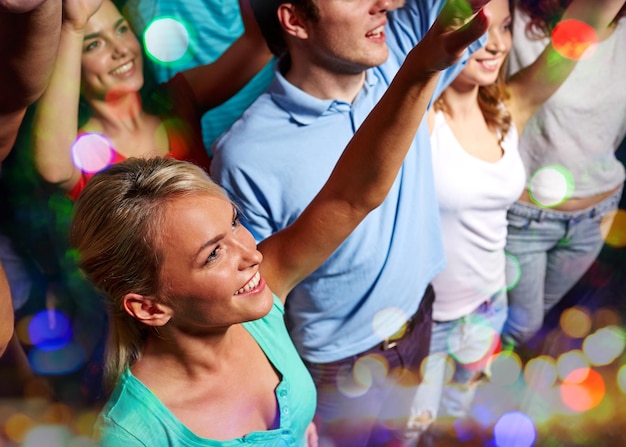 Foto fiesta, vacaciones, celebración, vida nocturna y concepto de la gente - amigos sonrientes saludando con la mano en un concierto en el club