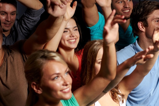 fiesta, vacaciones, celebración, vida nocturna y concepto de la gente - amigos sonrientes saludando con la mano en un concierto en el club