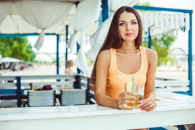 Fiesta de verano de estilo de vida. Mujer joven sexy con el pelo largo bebiendo cócteles en el bar de la playa.