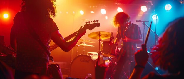 Fiestas de multitud en primera fila en un concierto de club nocturno con una banda de rock Siluetas de fans levantan las manos frente a luces brillantes en el escenario