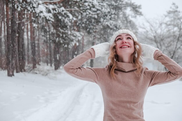 Fiestas de Navidad y concepto de temporada joven mujer feliz soplando nieve en el bosque de invierno naturaleza