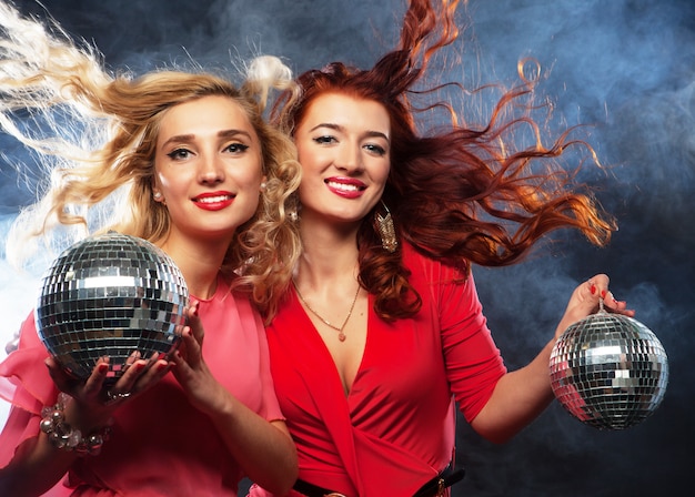 Fiesteras con bola de discoteca, felices y sonrientes