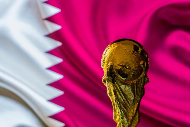 FIFA-Weltmeistertrophäe vor dem Hintergrund der Fahne von Katar