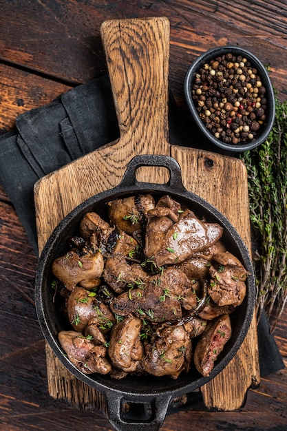 Fígado de frango assado com cebola em uma frigideira Fundo de madeira Vista superior