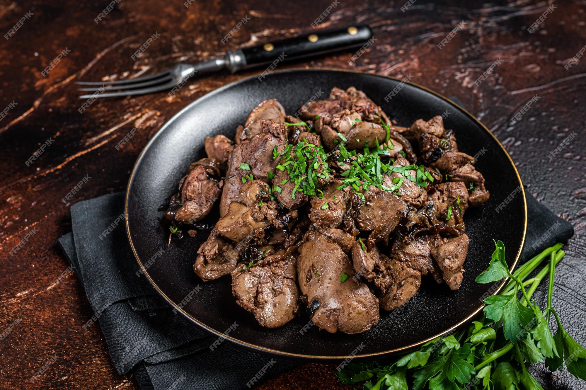 Fígado de frango frito com cebola e salsa em um prato fundo escuro