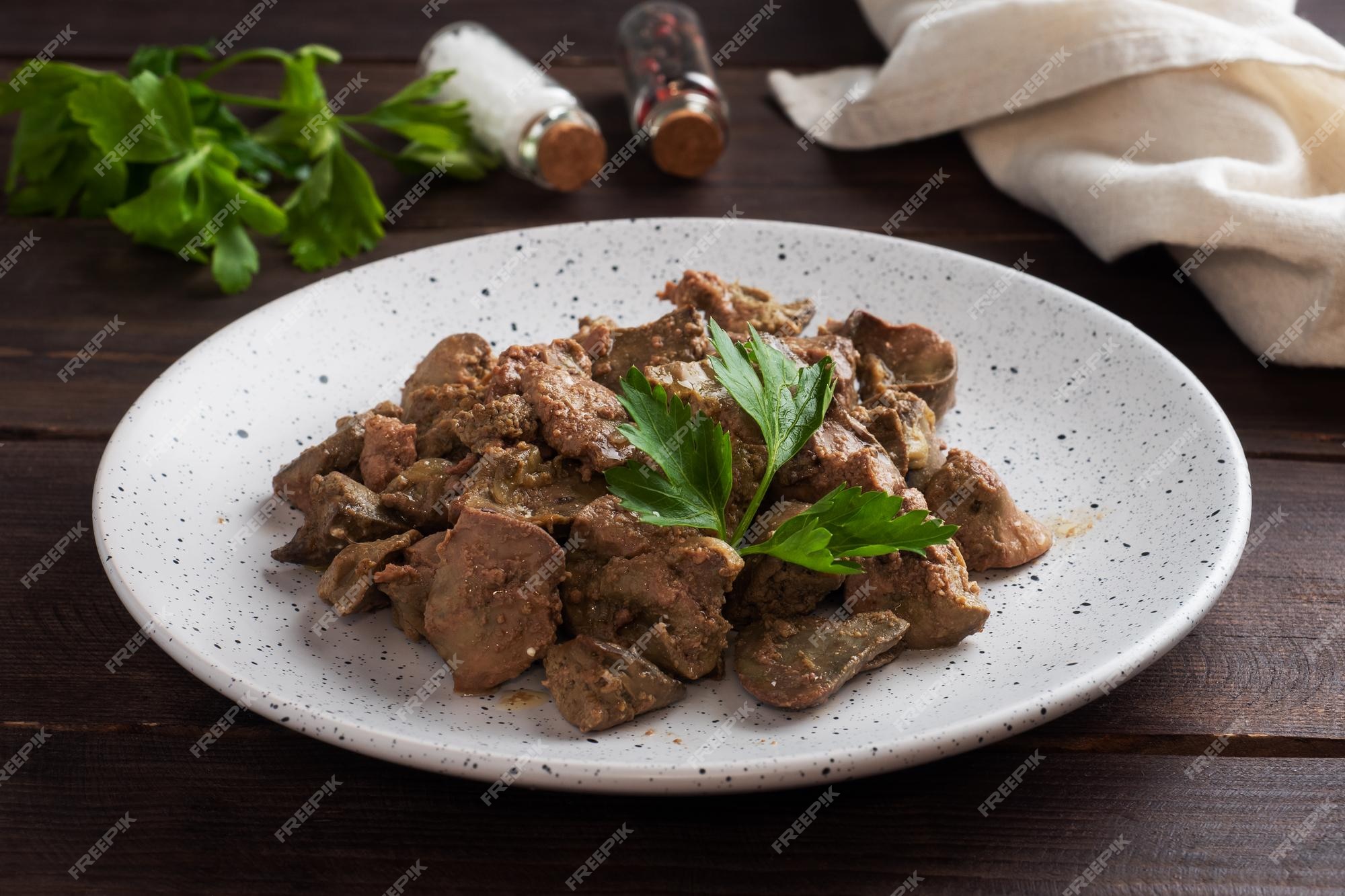 Fígado de frango frito ou assado com cebola e molho folhas de salsa verde  num prato prato de carne enriquecido com ferro