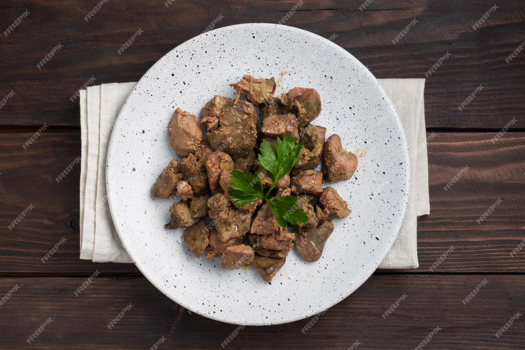 Fígado de frango frito ou assado com cebola e molho folhas de salsa verde  num prato prato de carne enriquecido com ferro