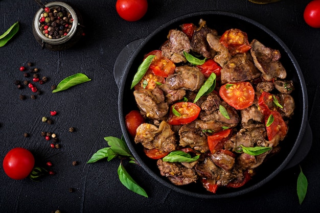 Fígado de galinha (miudezas) com cebola e tomate em uma frigideira em armênio. Postura plana. Vista do topo