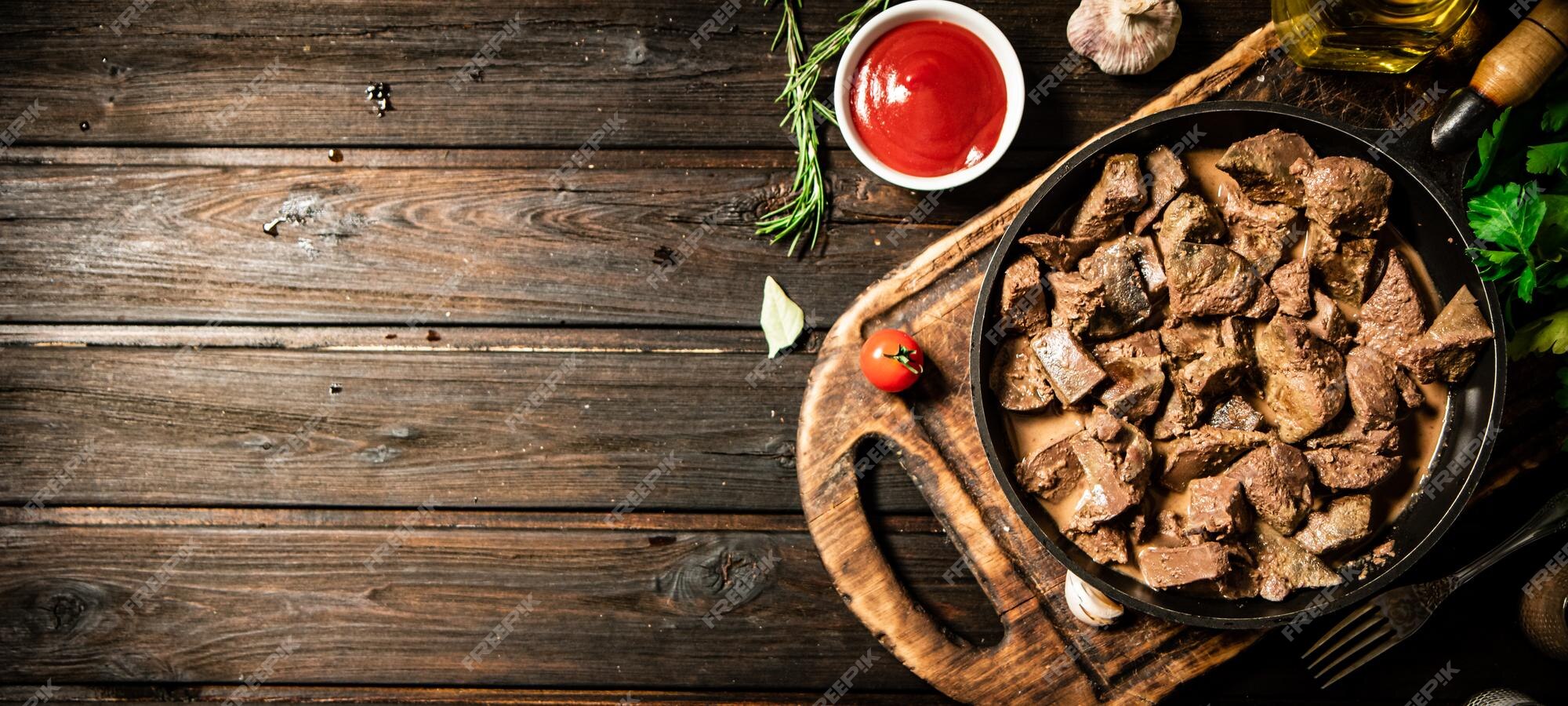 Fígado frito em uma frigideira em uma tábua com molho de tomate