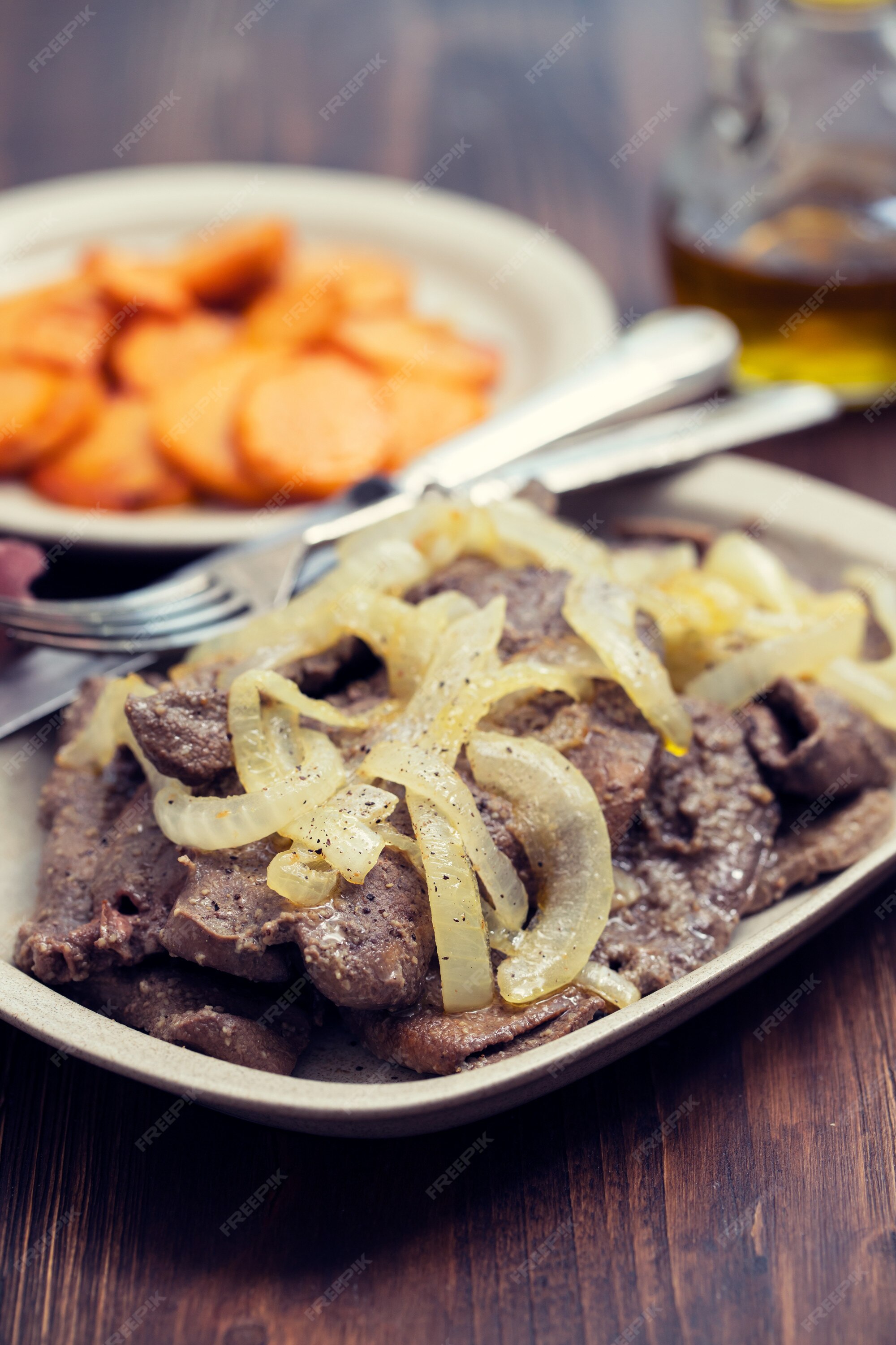 Fígado frito no prato branco e batata doce frita no prato