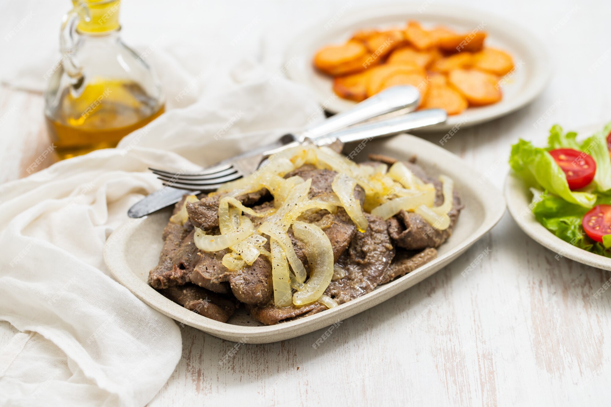 Fígado frito no prato branco e batata doce frita no prato