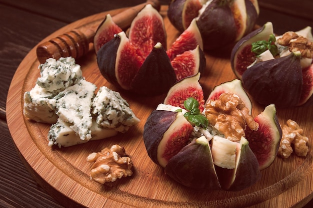 Figos de aperitivo com mel de noz de queijo azul em uma placa de madeira vista superior fechada sem pessoas