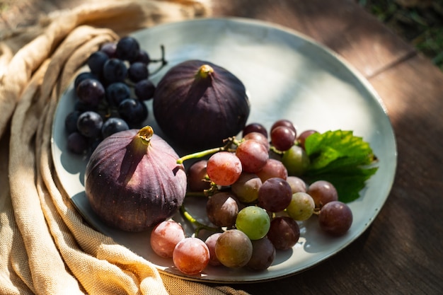 Figos e uvas em um prato sobre uma mesa de madeira