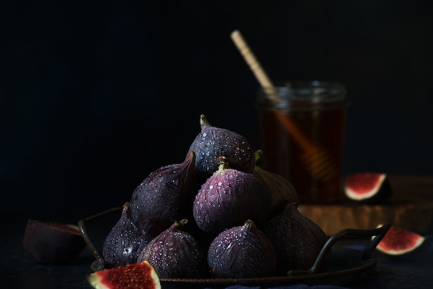 Figos maduros frescos em uma xícara de lata em um fundo escuro, orientação horizontal, frutas do sul