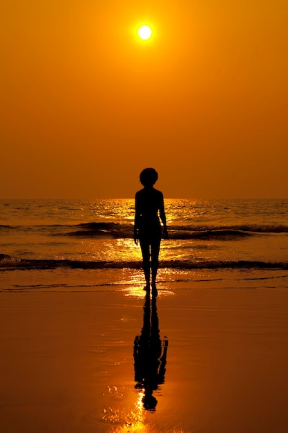 Figur einer Frau auf dem Hintergrund des Meeres und des Sonnenuntergangs