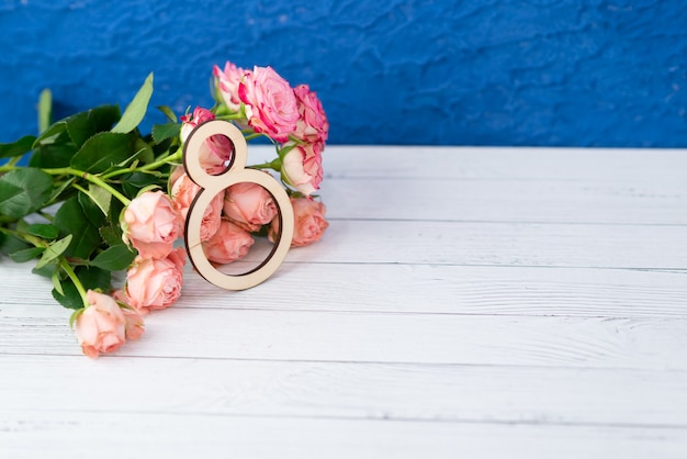 Figura 8 de madera con flores rosas sobre una mesa blanca. Dia Internacional de la Mujer. 8 de marzo