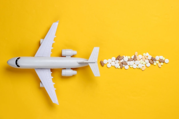 Foto figura de un avión de pasajeros con pastillas sobre un fondo amarillo.