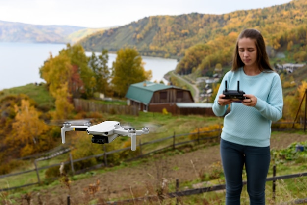 Figura borrada de menina controla um drone no outono fundo desfocado. Conceito de foco suave